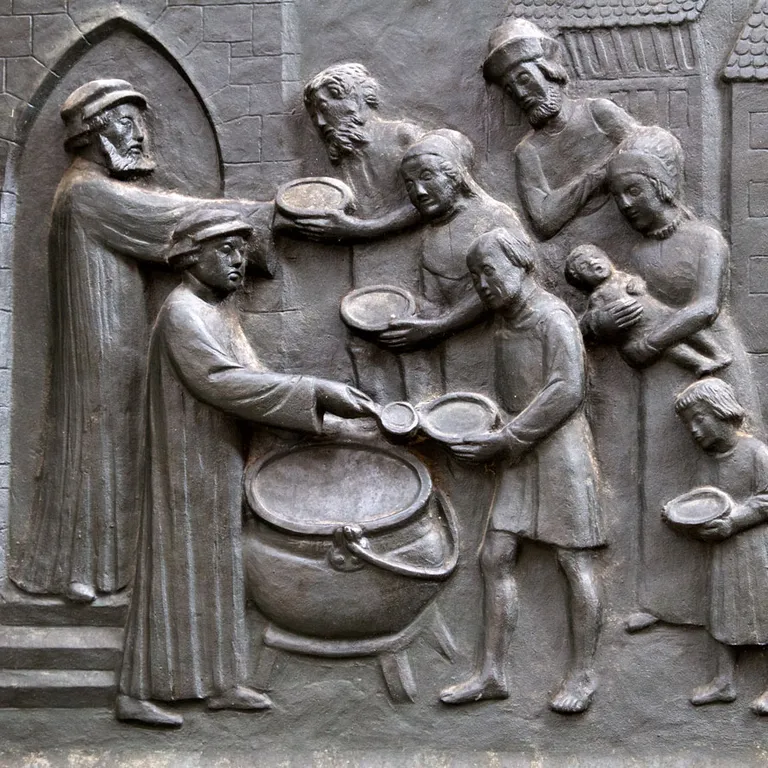 Relief zeigt Menschen, die Suppe an Bedürftige verteilen; mehrere Personen halten Schalen und erhalten Essen an einem großen Topf.