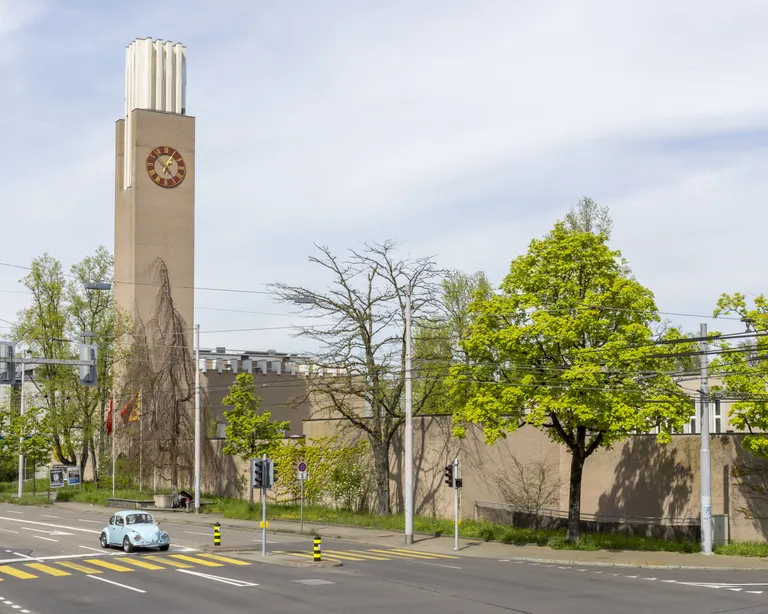 Kirche Glaubten an einer Straßenecke, umliegende Bäume und Autos im Vordergrund bei Tageslicht.