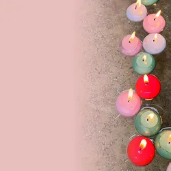 Mehrere bunte, brennende Teelichter stehen auf einem grauen Untergrund, links daneben eine rosa Fläche.