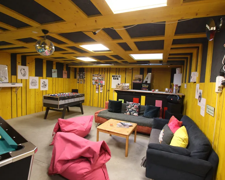 Der Freizeitraum «Underground» im Sonnegg mit Billardtisch, Tischkicker, Sofas, Sitzsäcken, einem Tresen und gelben Wänden, dekoriert mit Bildern.