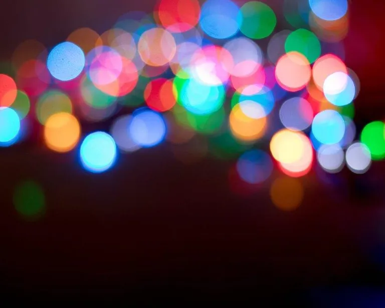 Verschwommene, bunte Lichter vor dunklem Hintergrund, erzeugen einen stimmungsvollen, abstrakten Effekt.
