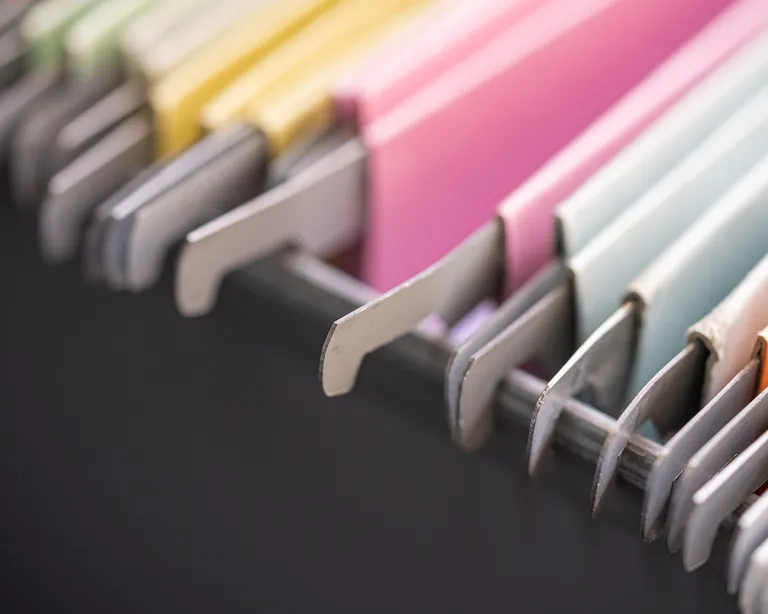 Bunte Hängeregister in einem Aktenschrank, die Register sind sortiert und nebeneinander angeordnet.