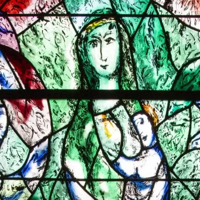 Grünliches Kirchenfenster mit stilisierter, weiblicher Figur in der Mitte und abstrakten, farbigen Formen im Hintergrund.
