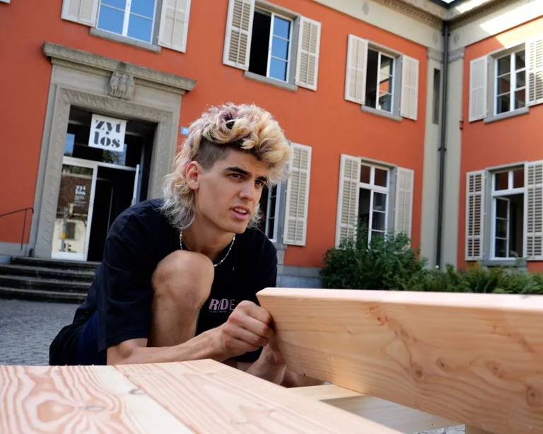 Junger Mann sitzt vor einem Kirchgemeindehaus