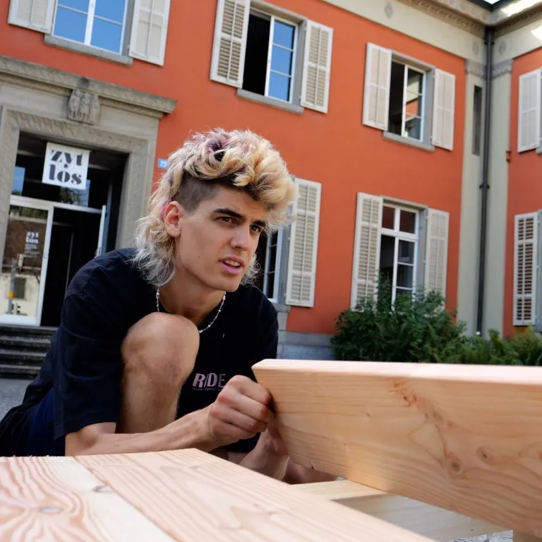 Junger Mann sitzt vor einem Kirchgemeindehaus