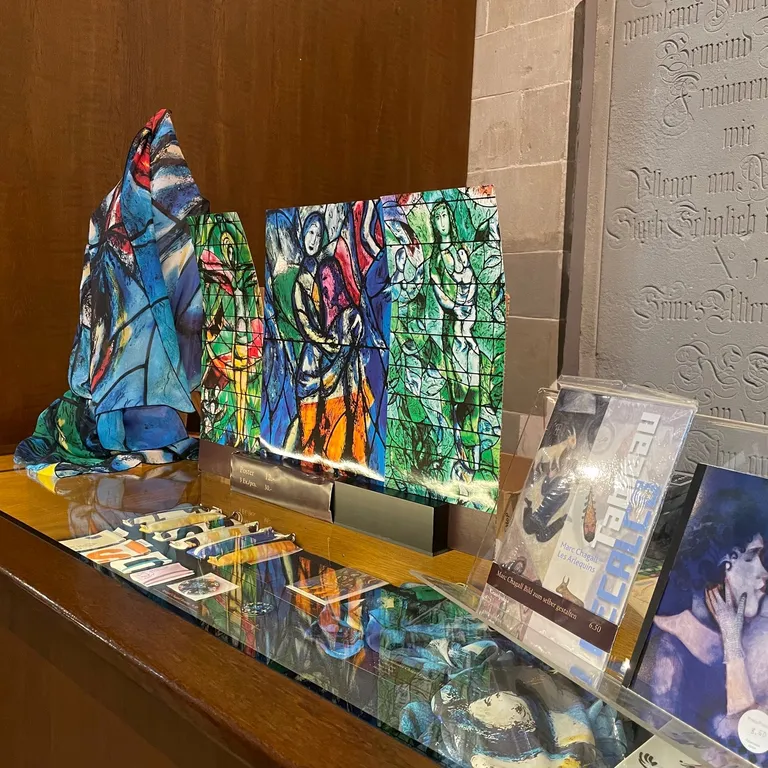 Bunte abstrakte Skulpturen und gerahmte Fotos stehen auf einer Glasvitrine vor einer Holz- und Steinwand.