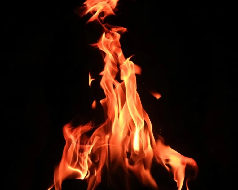 Eine orange-gelbe Flamme lodert vor schwarzem Hintergrund.