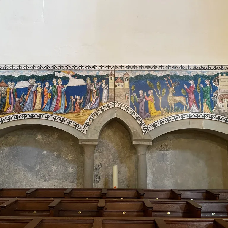 Wandgemälde mit religiösen Szenen über zwei romanischen Bögen, davor Holzbänke, auf hellem Hintergrund.