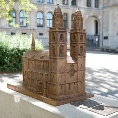 Miniaturmodell aus Bronze des Grossmünsters mit seinen zwei Türmen im Freien, im Hintergrund die theologische Fakultät und Bäume.