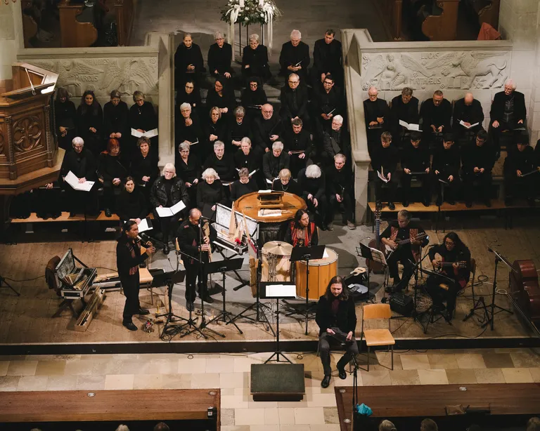 Blick von oben auf einen Chor und ein Orchester, die in einer Kirche gemeinsam musizieren.