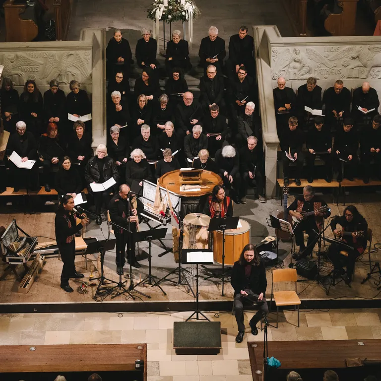 Blick von oben auf einen Chor und ein Orchester, die in einer Kirche gemeinsam musizieren.