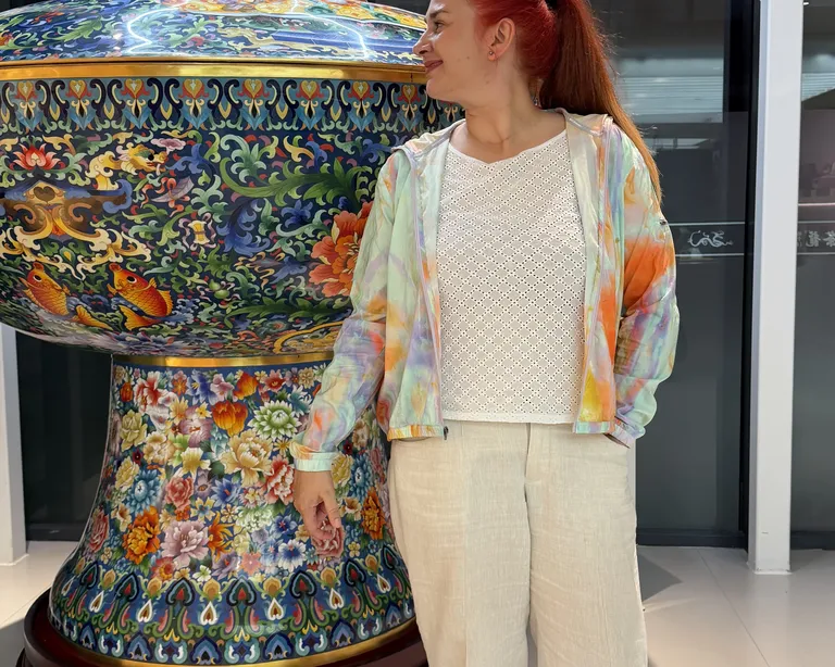 Organistin Sofija Grgur steht vor einer bunt verzierten, grossen Vase in einem modernen Innenraum.
