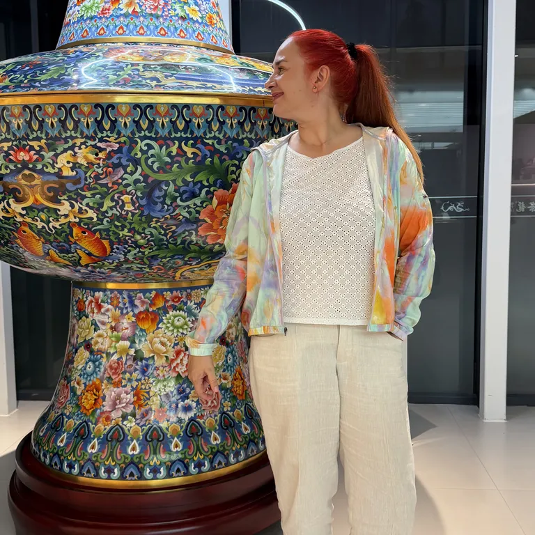 Organistin Sofija Grgur steht vor einer bunt verzierten, grossen Vase in einem modernen Innenraum.