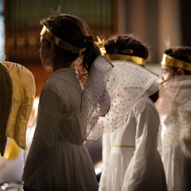 Mehrere Kinder mit Engelflügel stehen nebeneinander bei einer Aufführung in einer Kirche.