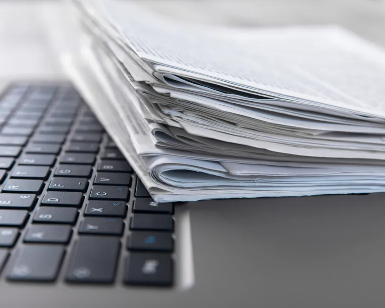 Stapel Papier liegt auf einer Computertastatur.