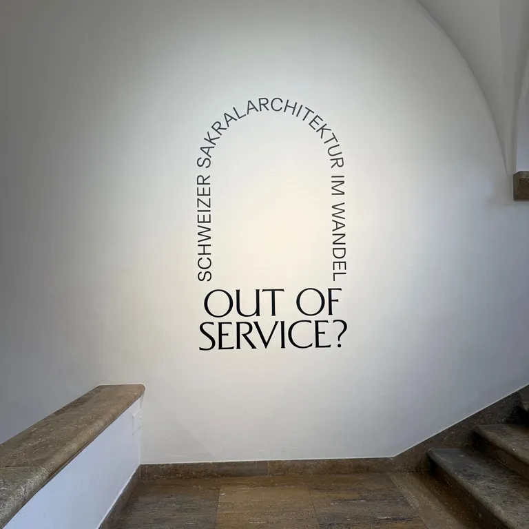 Alt-Text: Menschen tanzen auf einer runden Bühne in einem hellen Saal mit großen Fenstern, Zuschauer sitzen im Halbkreis.