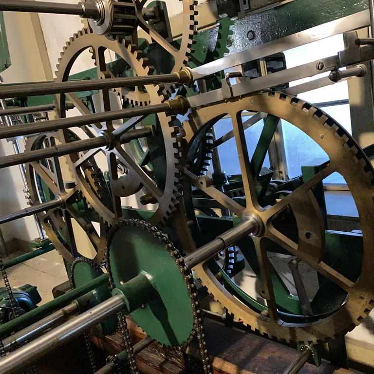 Grosse Zahnräder aus Metall greifen ineinander in einem mechanischen Uhrwerk./Large metal gears mesh with one another in a mechanical watch movement.