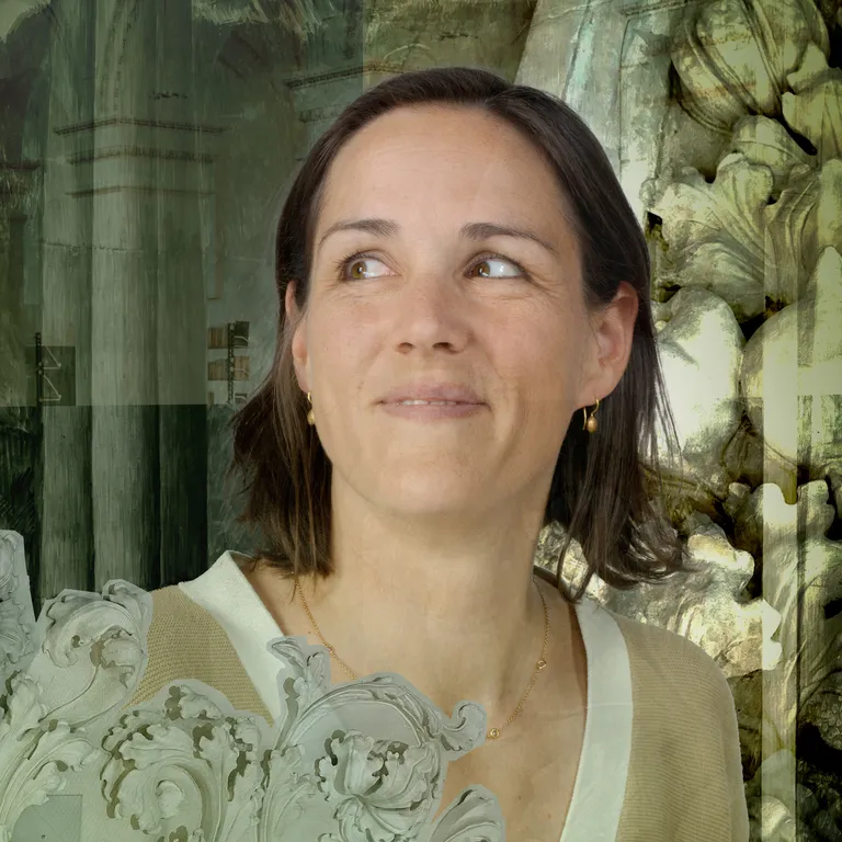 Frau mit braunen Haaren und hellem Oberteil blickt lächelnd nach links, Hintergrund mit Stein- und Glasstrukturen.