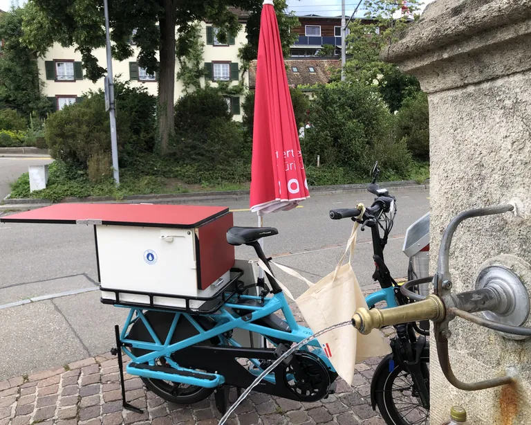 Das chile mobil unterwegs im Kirchenkreis zehn ist ein Velo neben dem Brunnen.