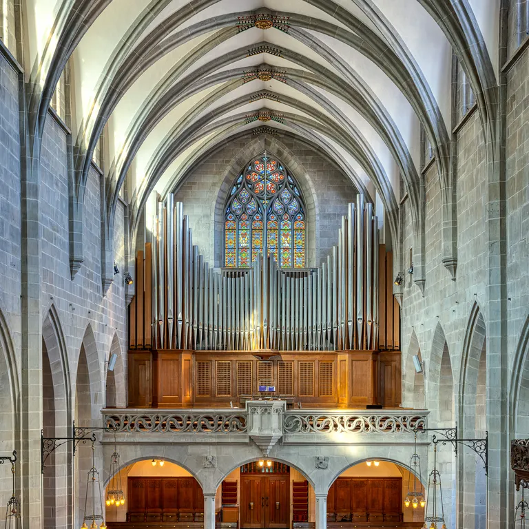 Helles Kircheninnere mit hohen Gewölbedecken, Holzbänken und großer Orgel an der Rückwand.