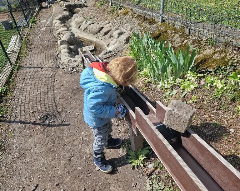 Kleines Kind von der Spielgruppe Gartespatze in Höngg spielt mit Wasser.